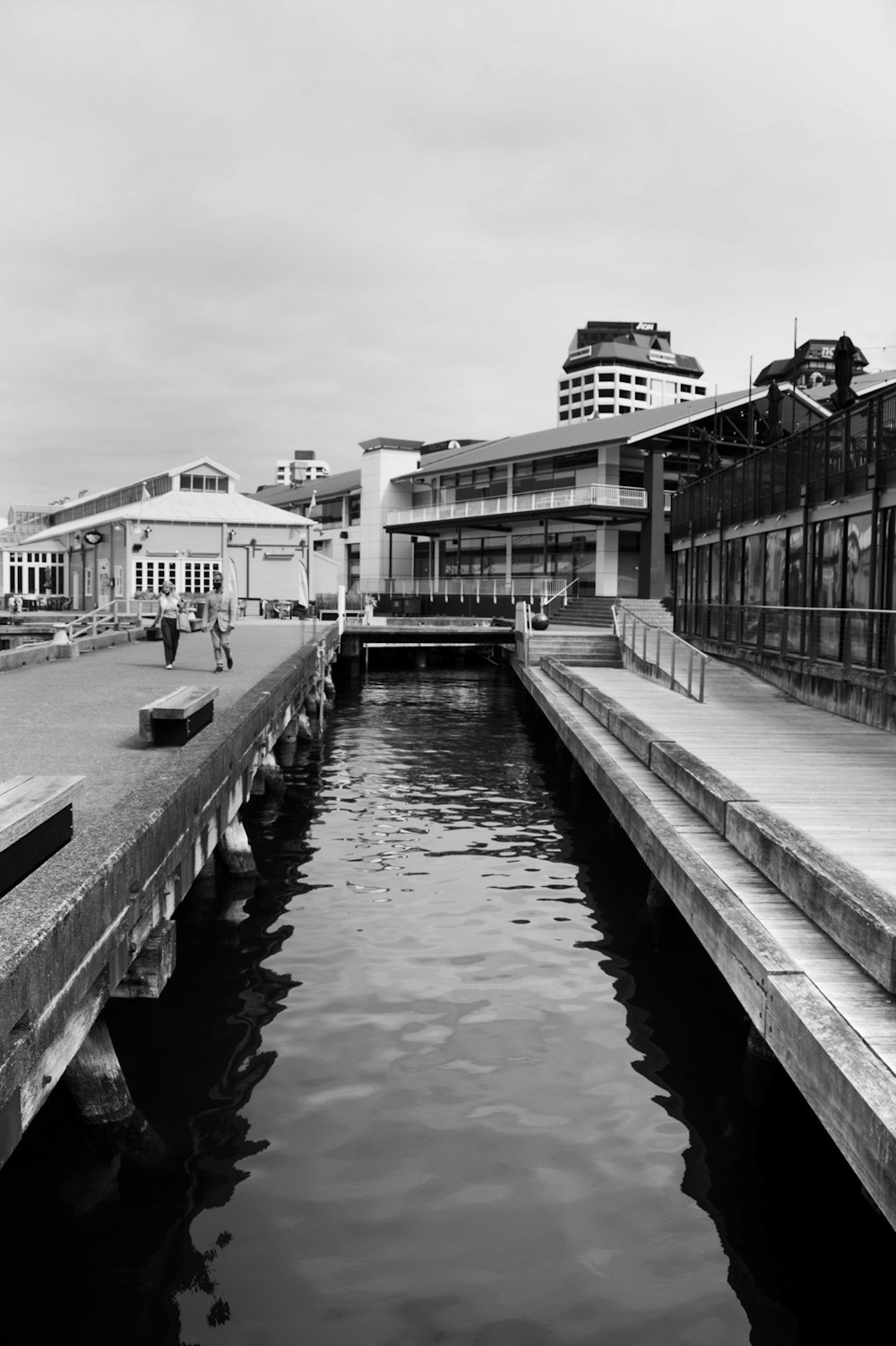 a black and white photo of a canal in a city