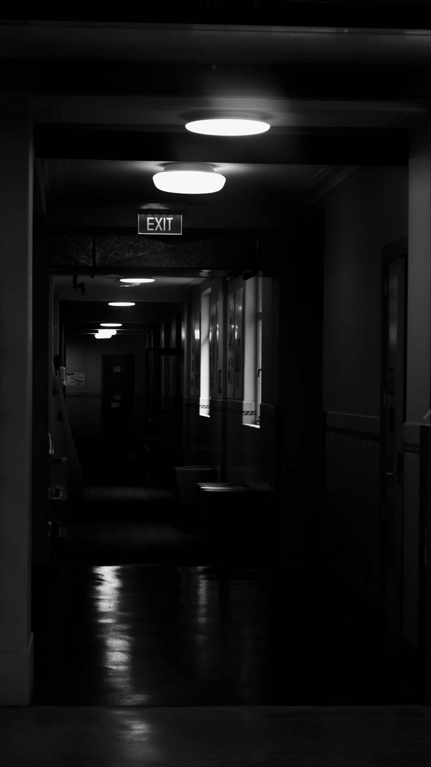 A dark hallway with an exit sign on the wall