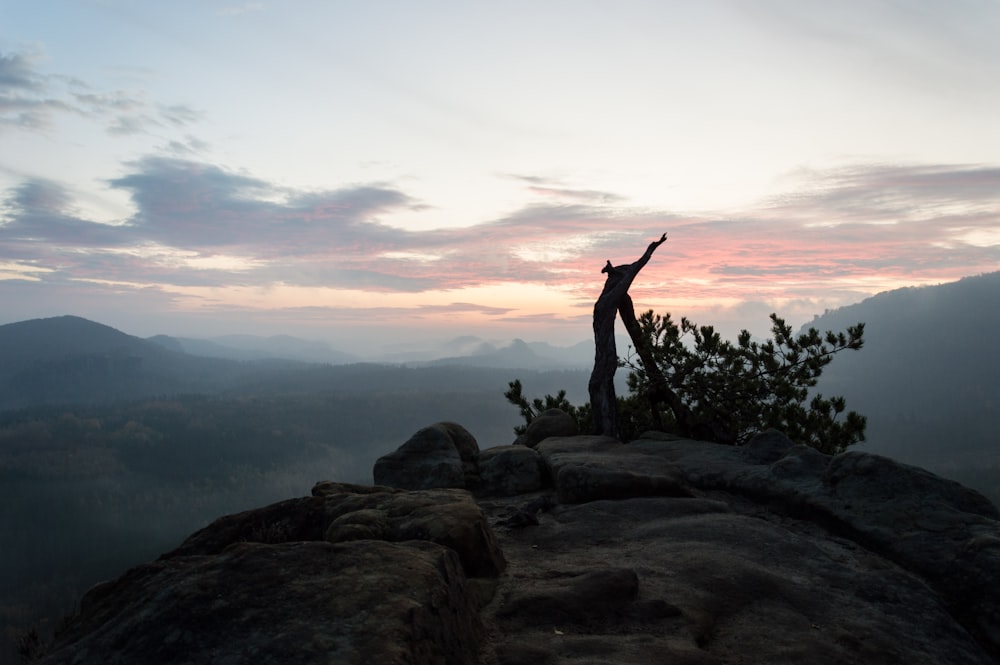 a person standing on top of a mountain with their arms in the air