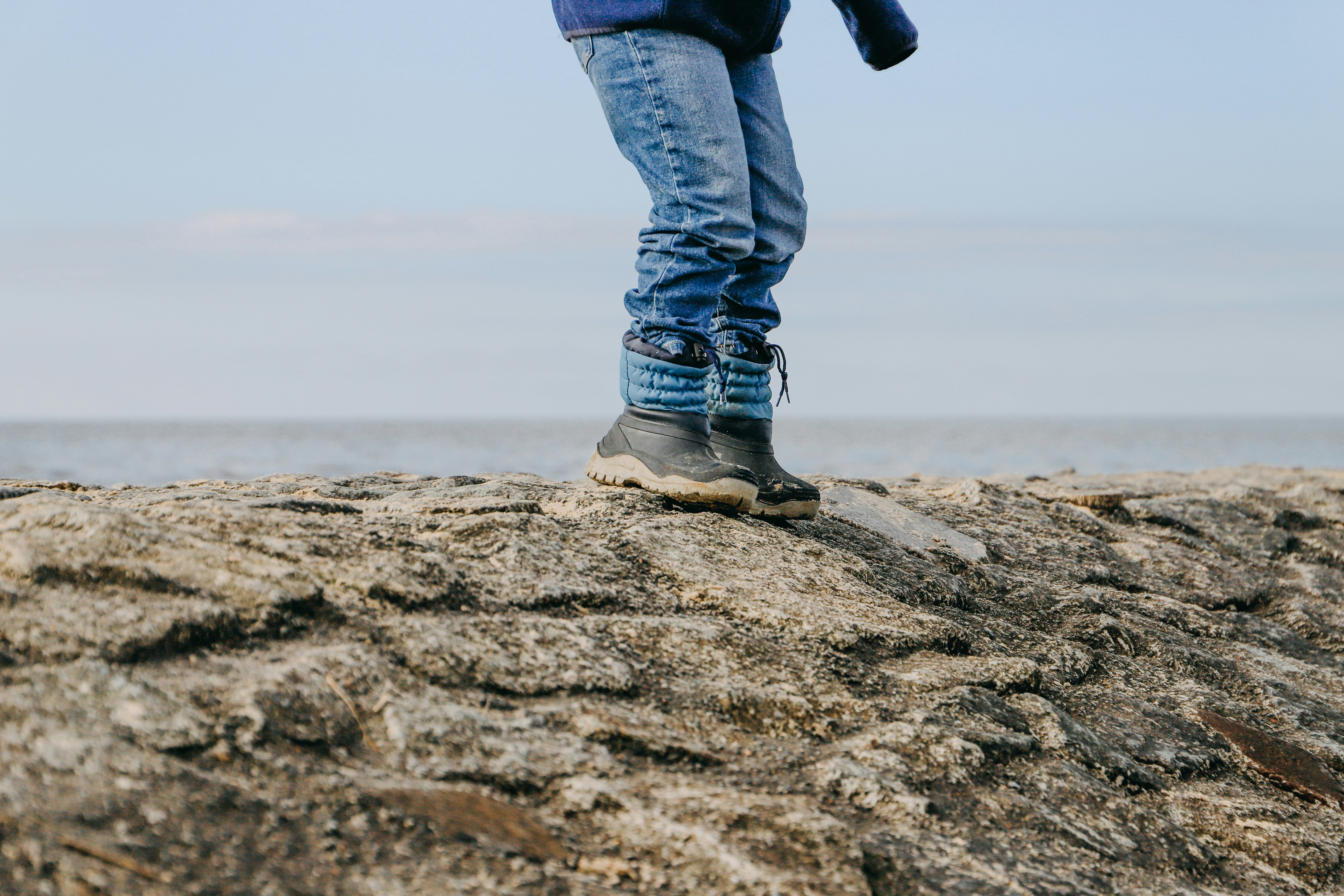 a person standing on top of a rock near the ocean