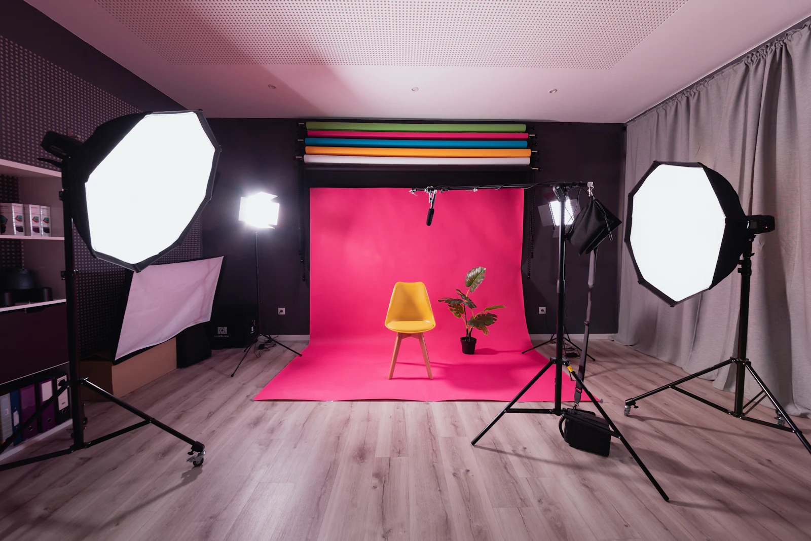 A photography studio with a pink paper backdrop and a yellow chair.