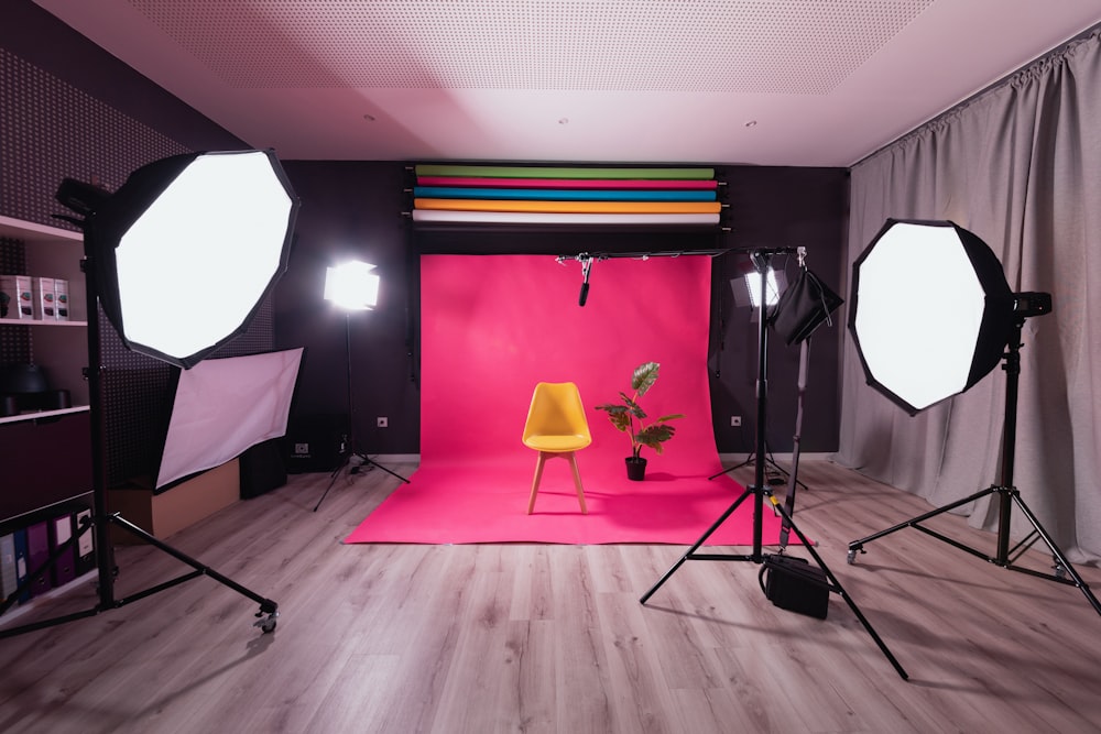 um estúdio fotográfico com um pano de fundo rosa e uma cadeira amarela