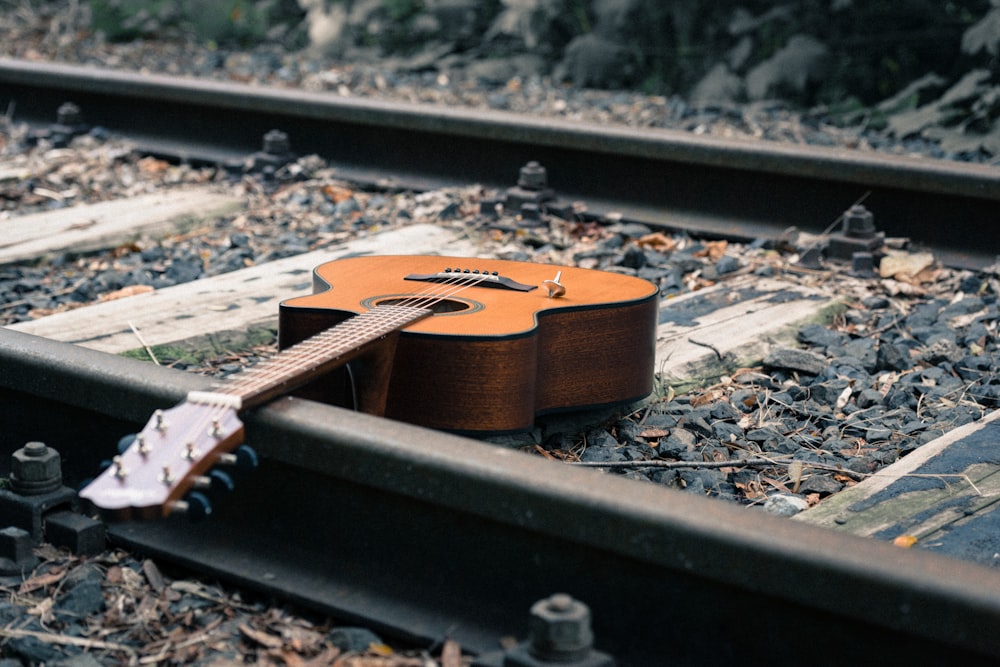 a guitar sitting on the tracks of a train track