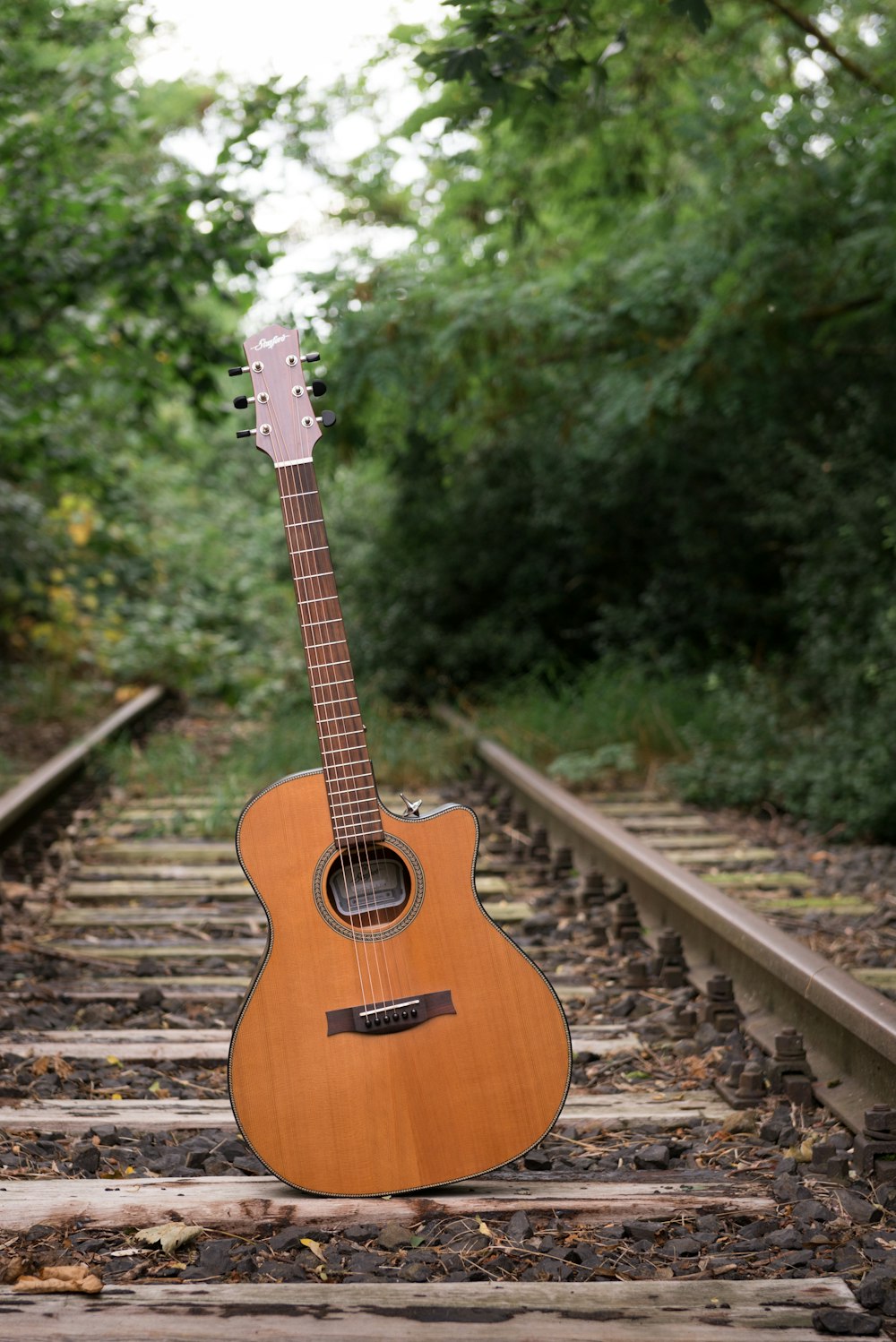 an acoustic guitar sitting on a train track