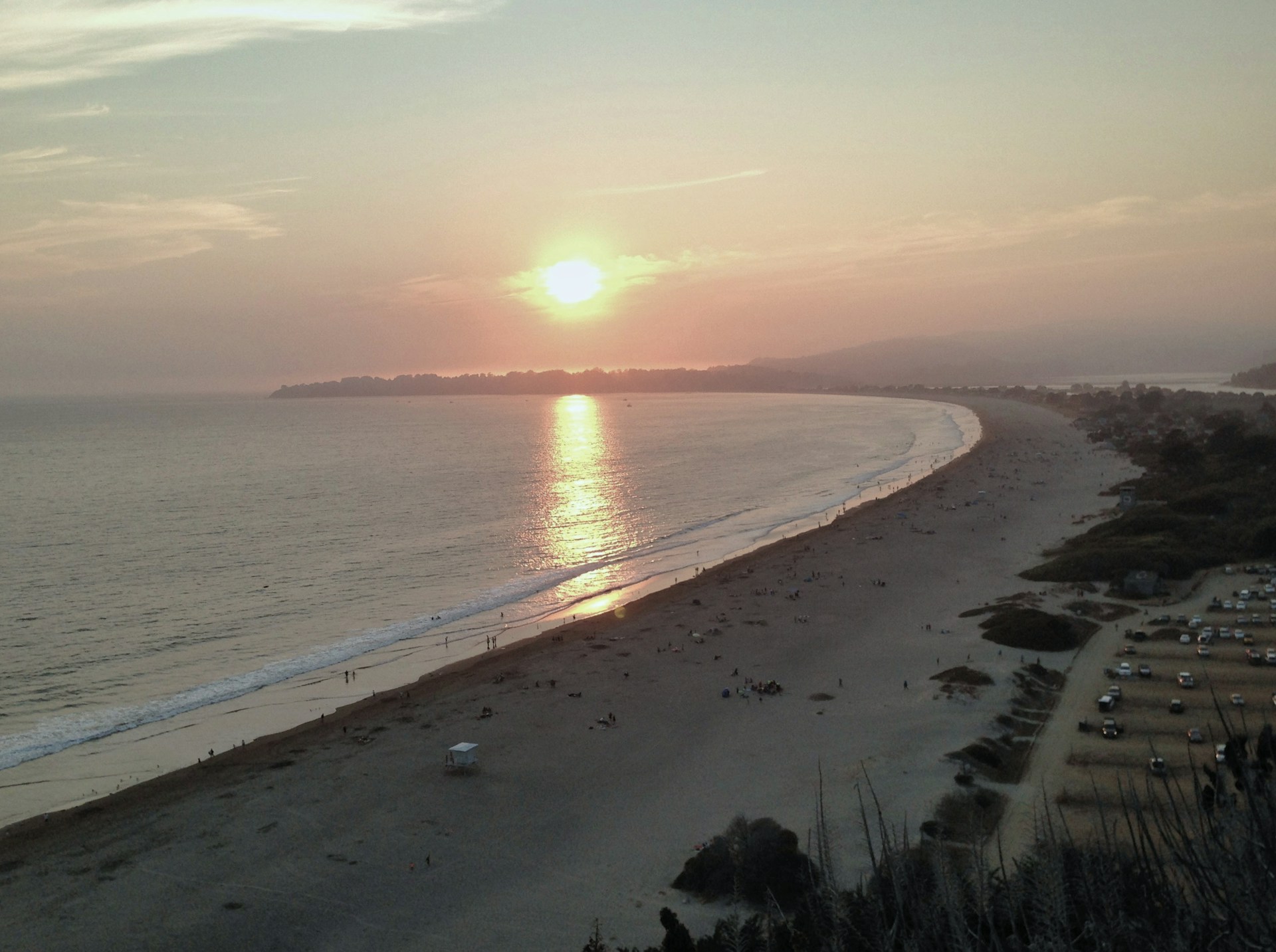 the sun is setting over the beach and the ocean