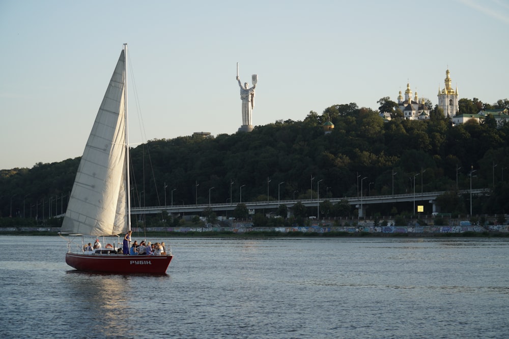 un velero en un cuerpo de agua con una estatua en el fondo