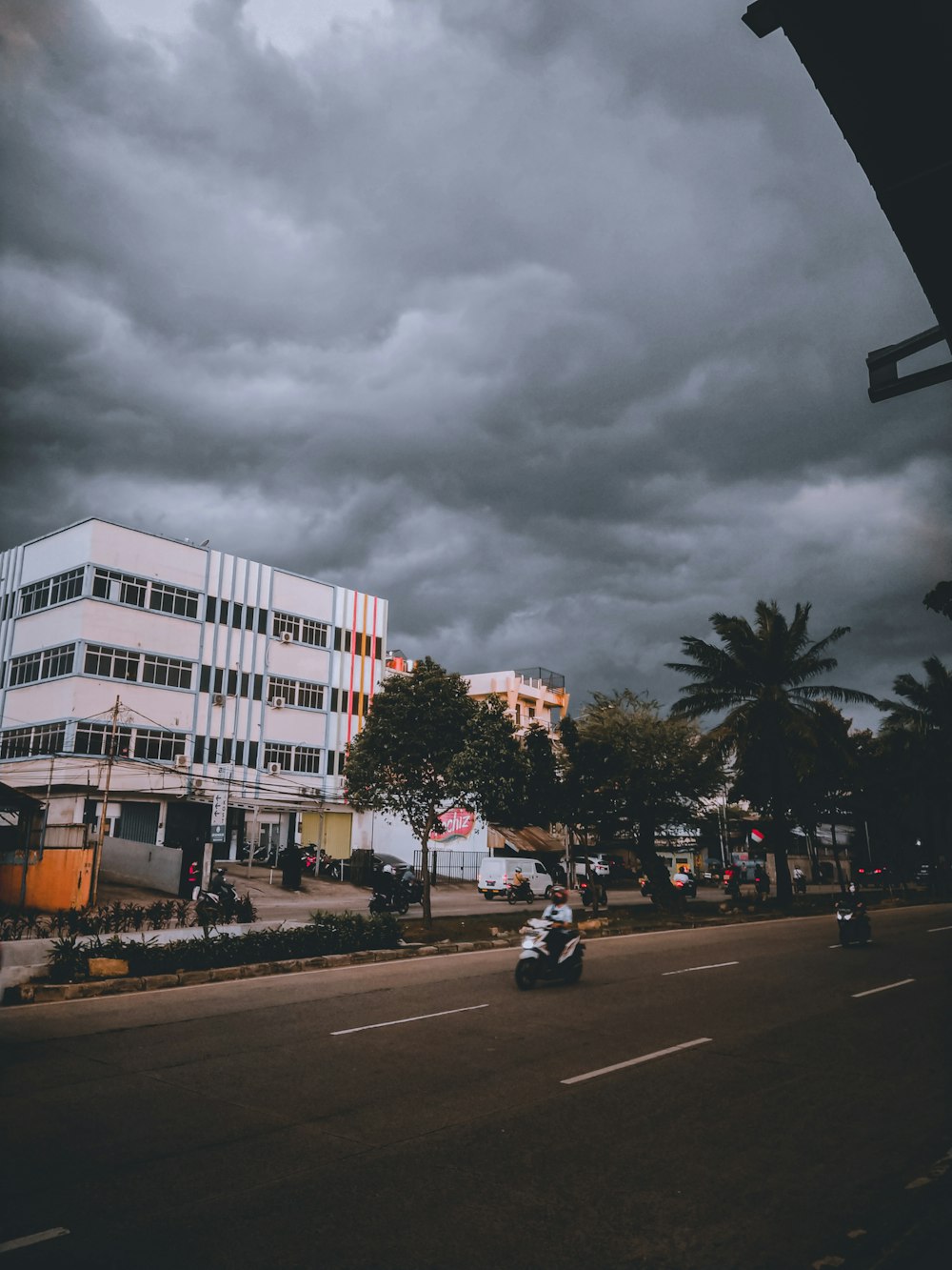 a person riding a motorcycle down a street under a cloudy sky