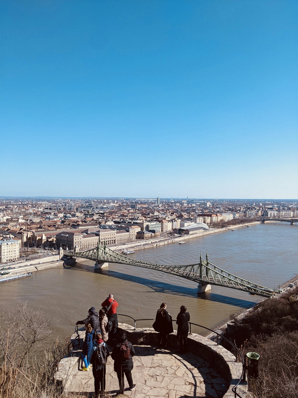 a group of people standing on top of a hill next to a river