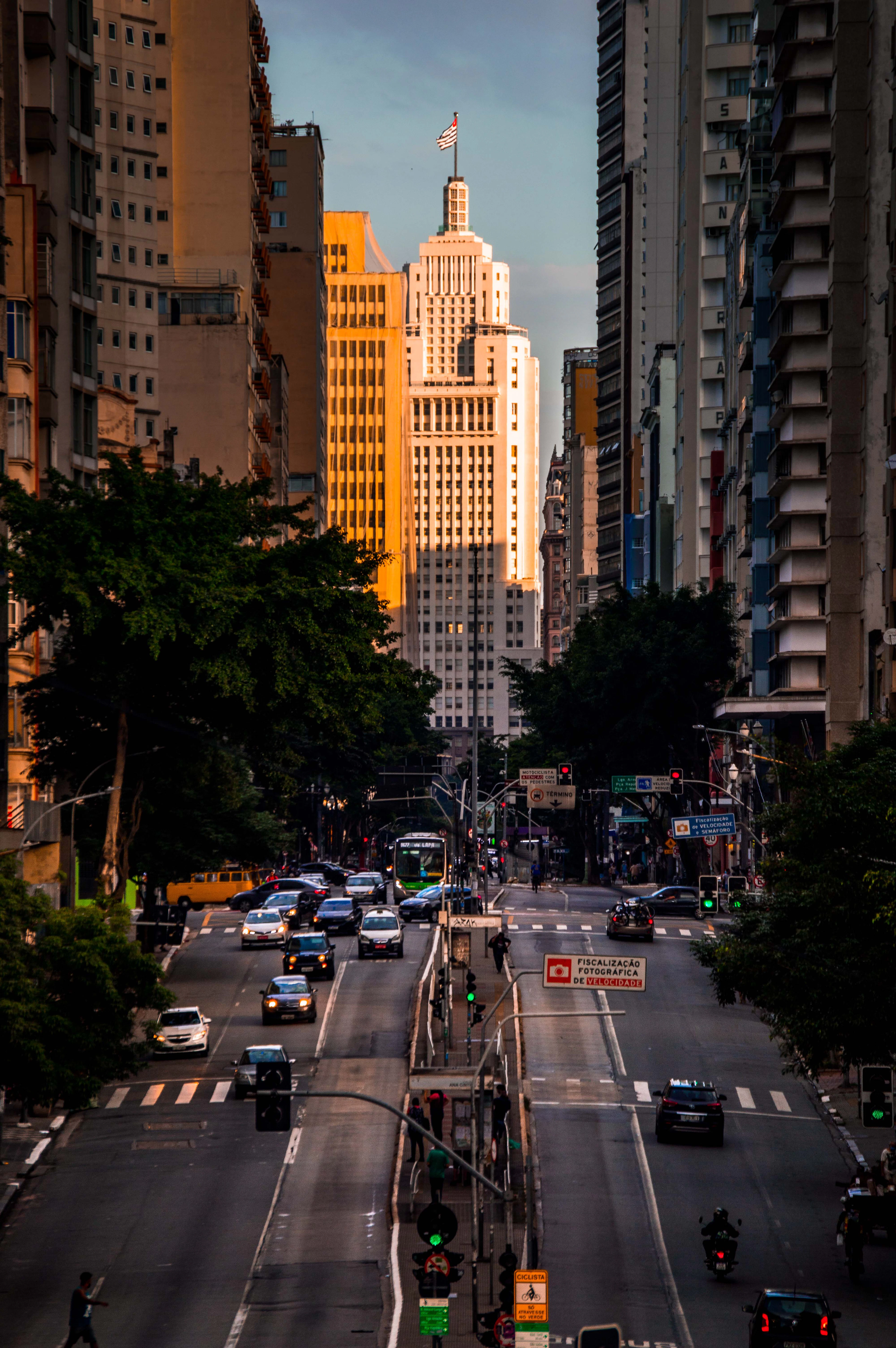 Traffic on a downtown Sao Paulo avenue at sunset with the tower of the Edificio Altino Arantes (Banespa) rising at the end of the street