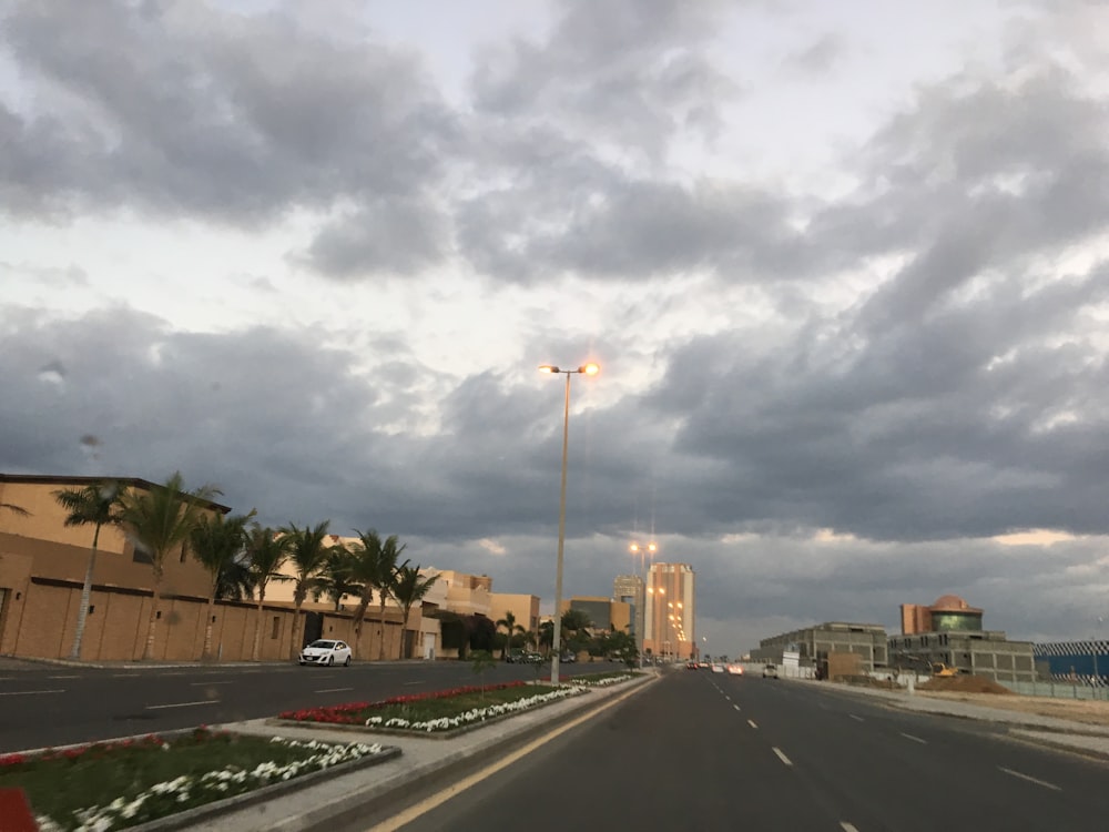 a street with cars driving down it under a cloudy sky