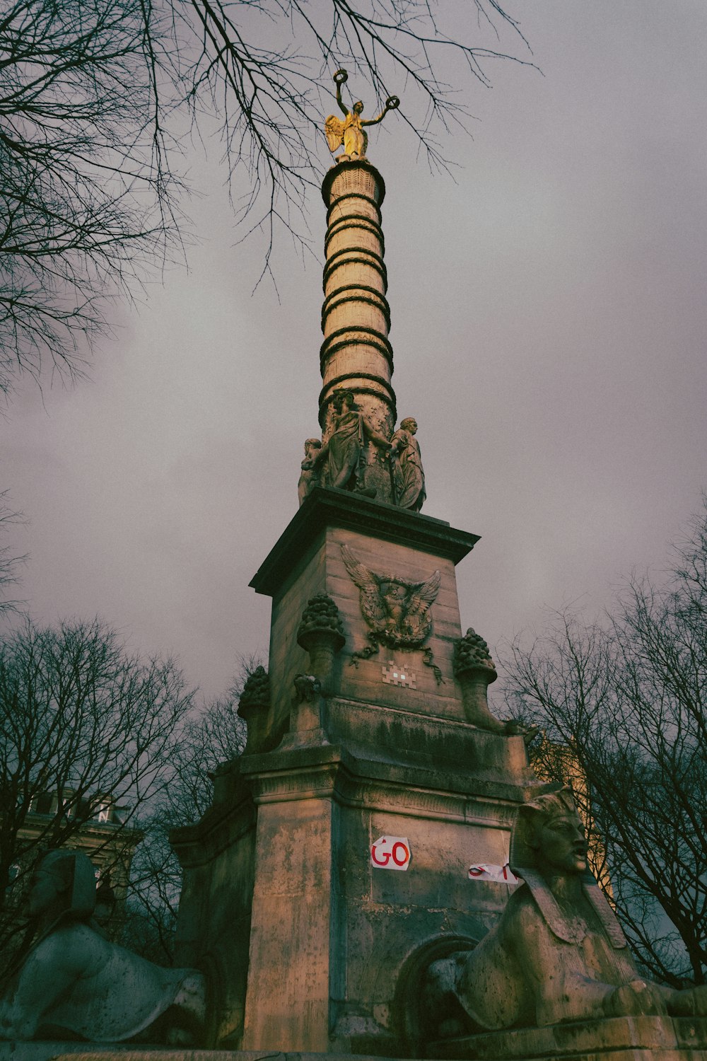 une haute tour surmontée d’une statue
