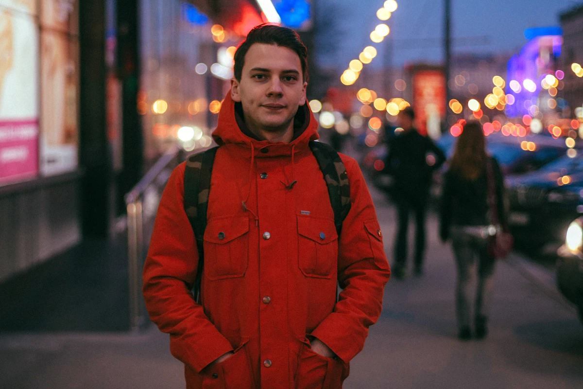 Man in red insulated jacket walking on city sidewalk in cold weather