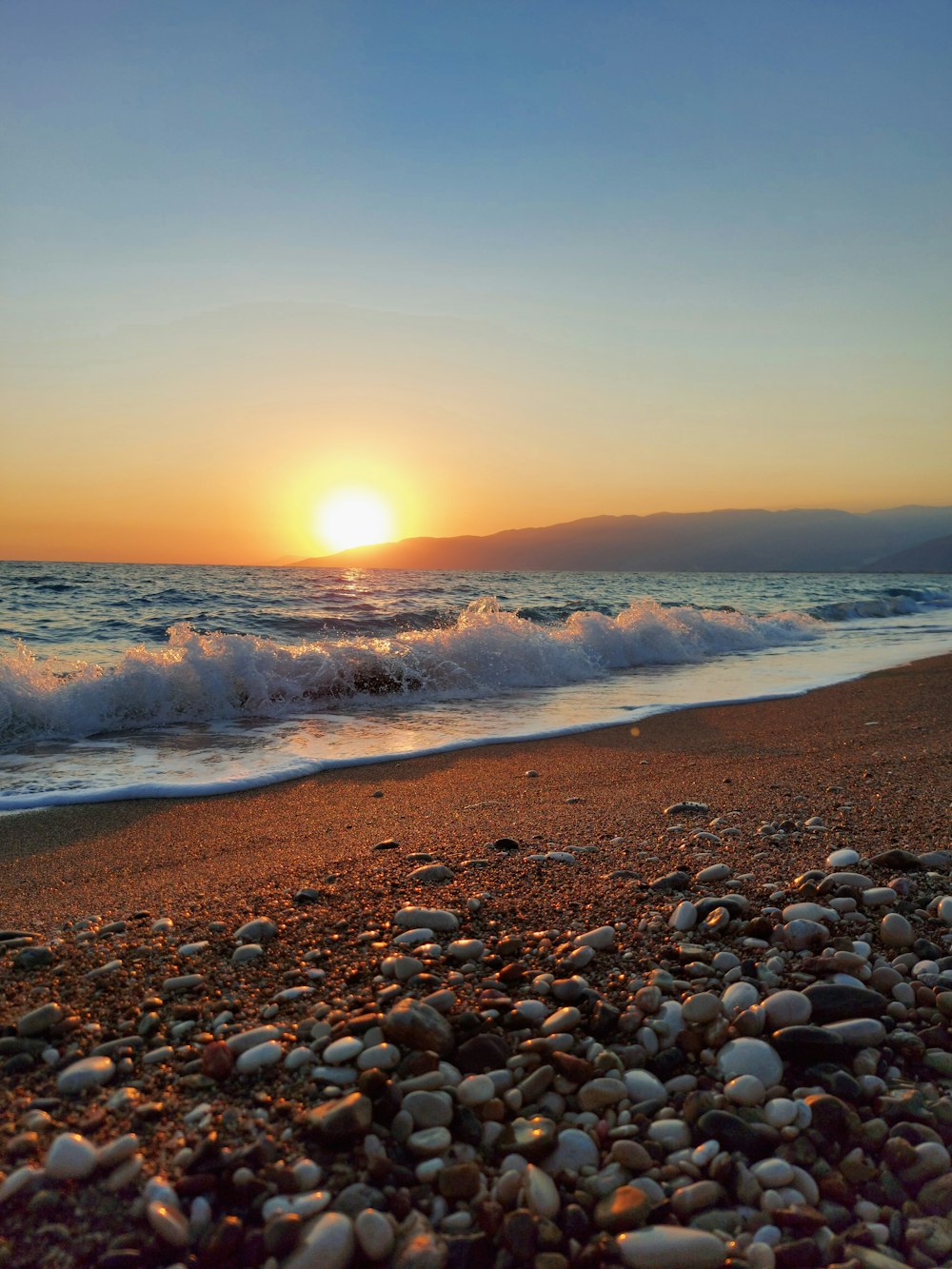 the sun is setting over the ocean on the beach