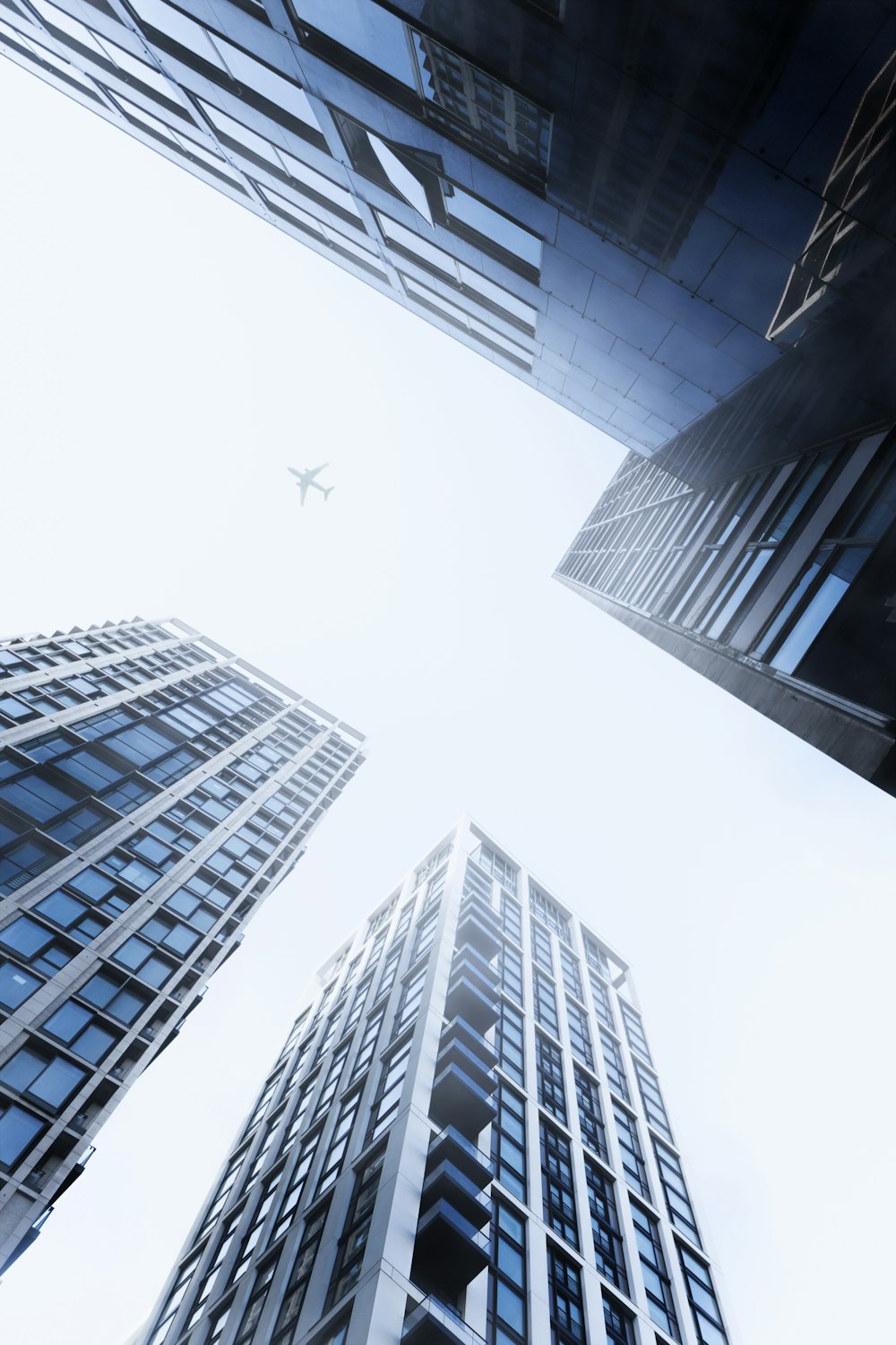 um grupo de edifícios altos com um avião voando no céu
