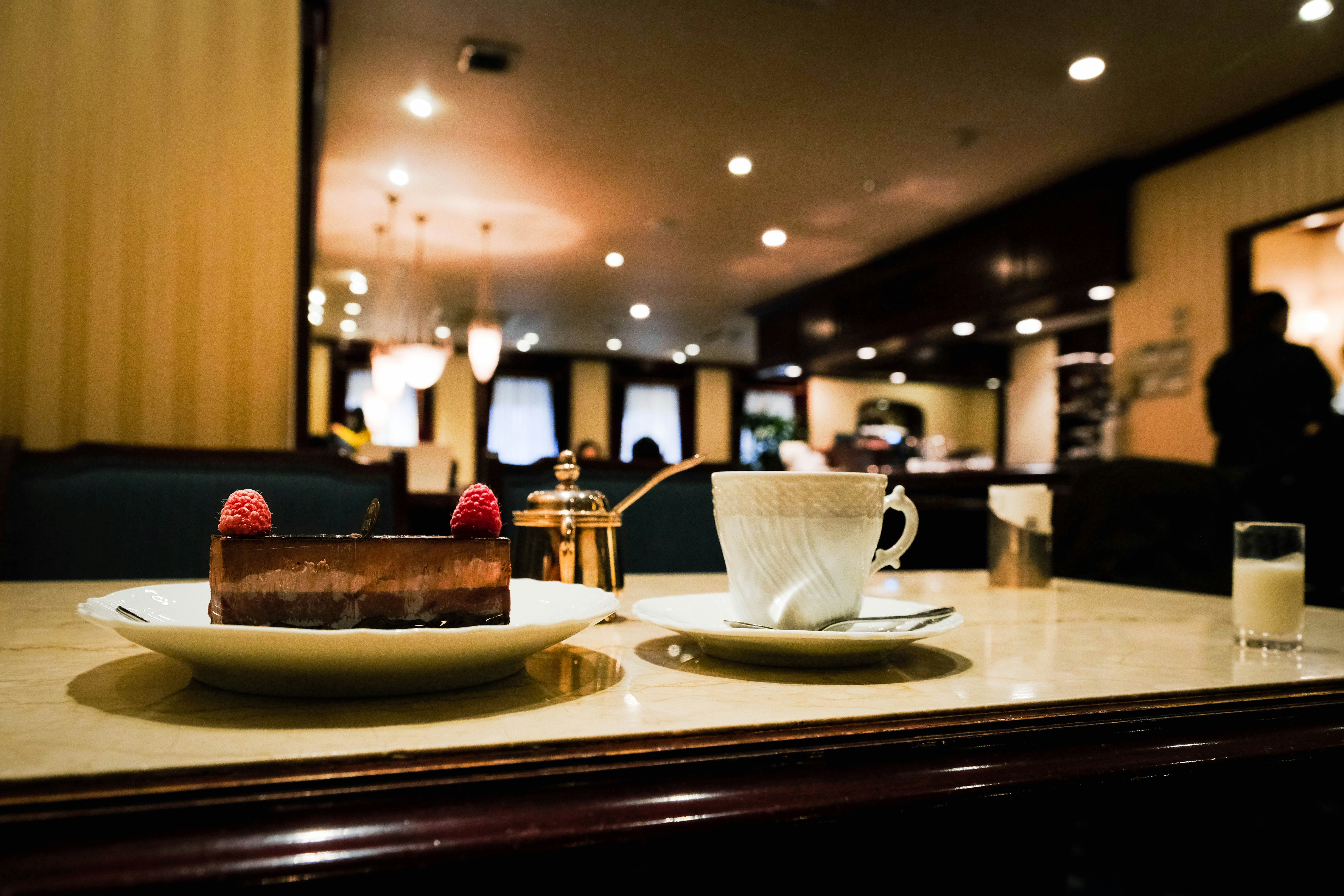 a table topped with a plate of cake and a cup of coffee