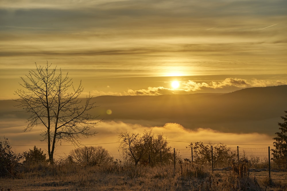 the sun is setting over a foggy valley