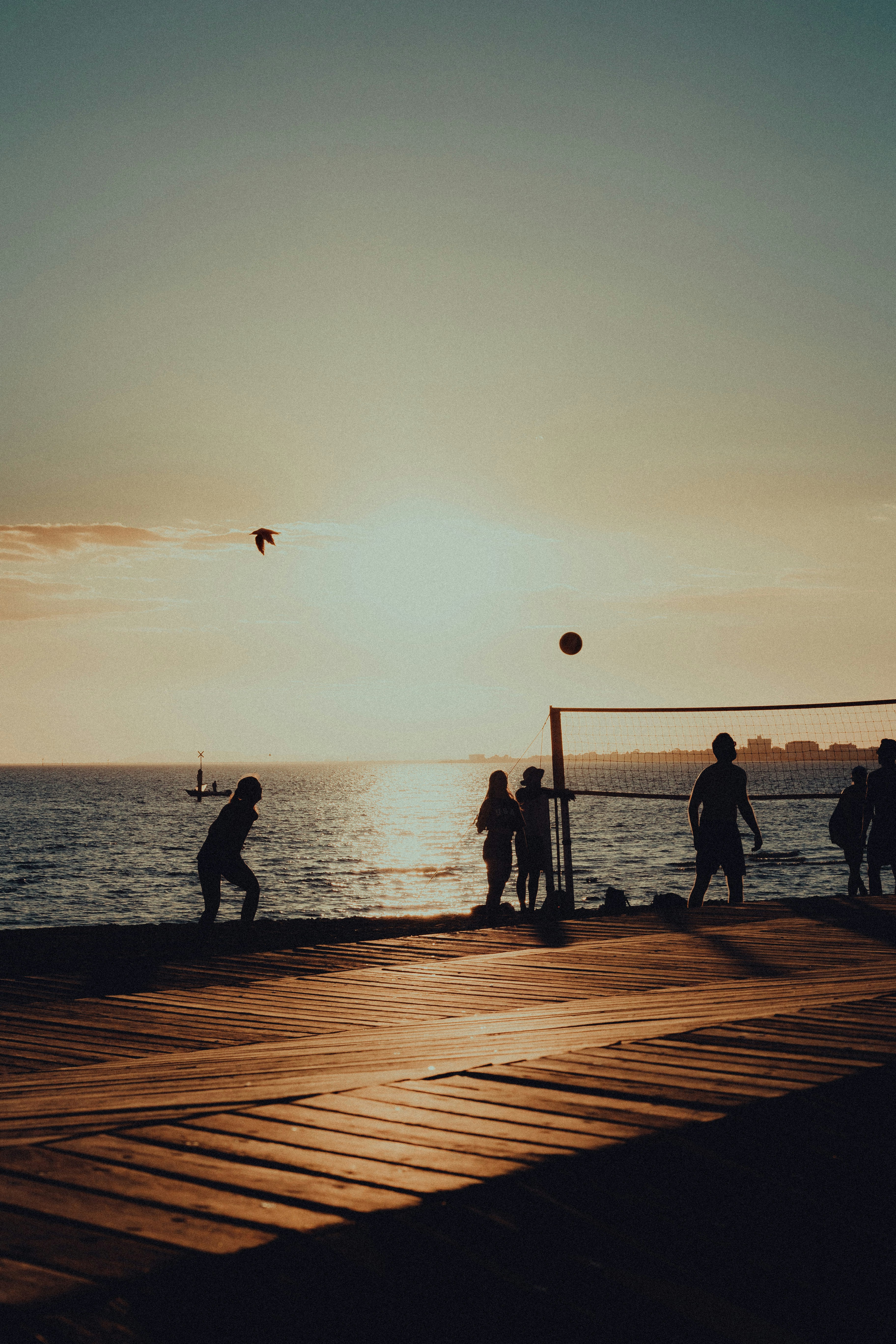 a group of people playing volleyball on a pier