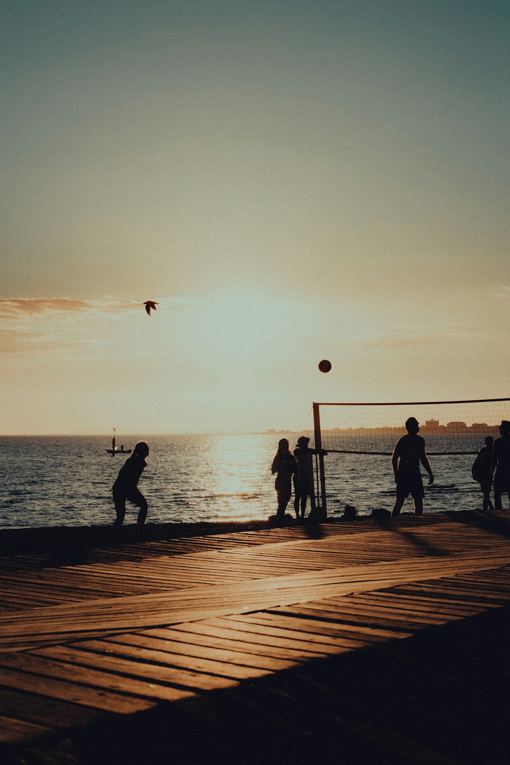 a group of people playing volleyball on a pier