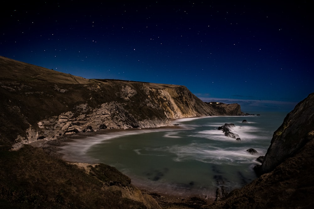 a view of a beach at night with the moon in the sky