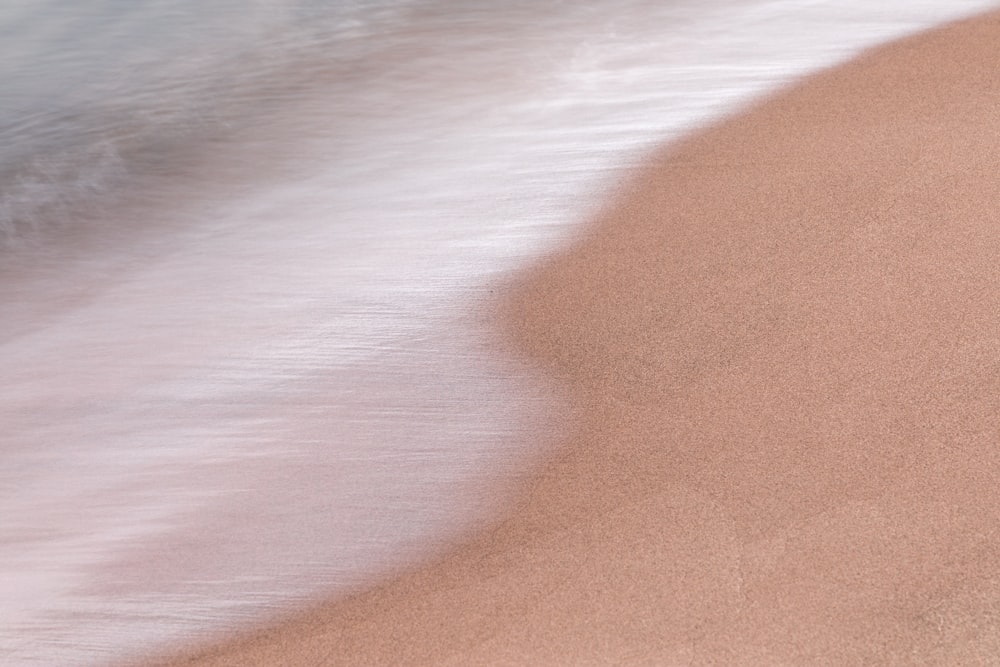 a blurry photo of a beach with a wave coming in