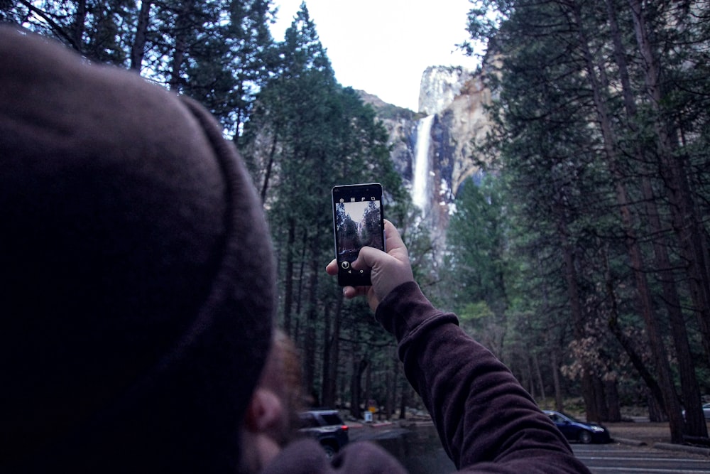 a person taking a picture of a waterfall