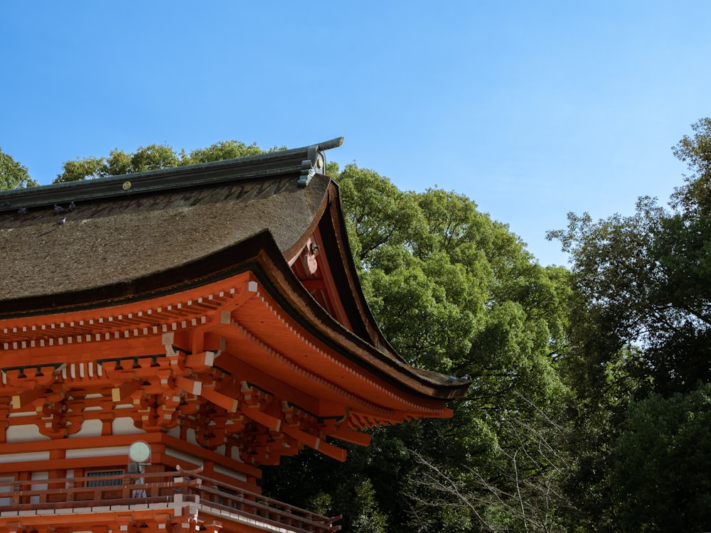 a tall orange building with a roof and trees in the background