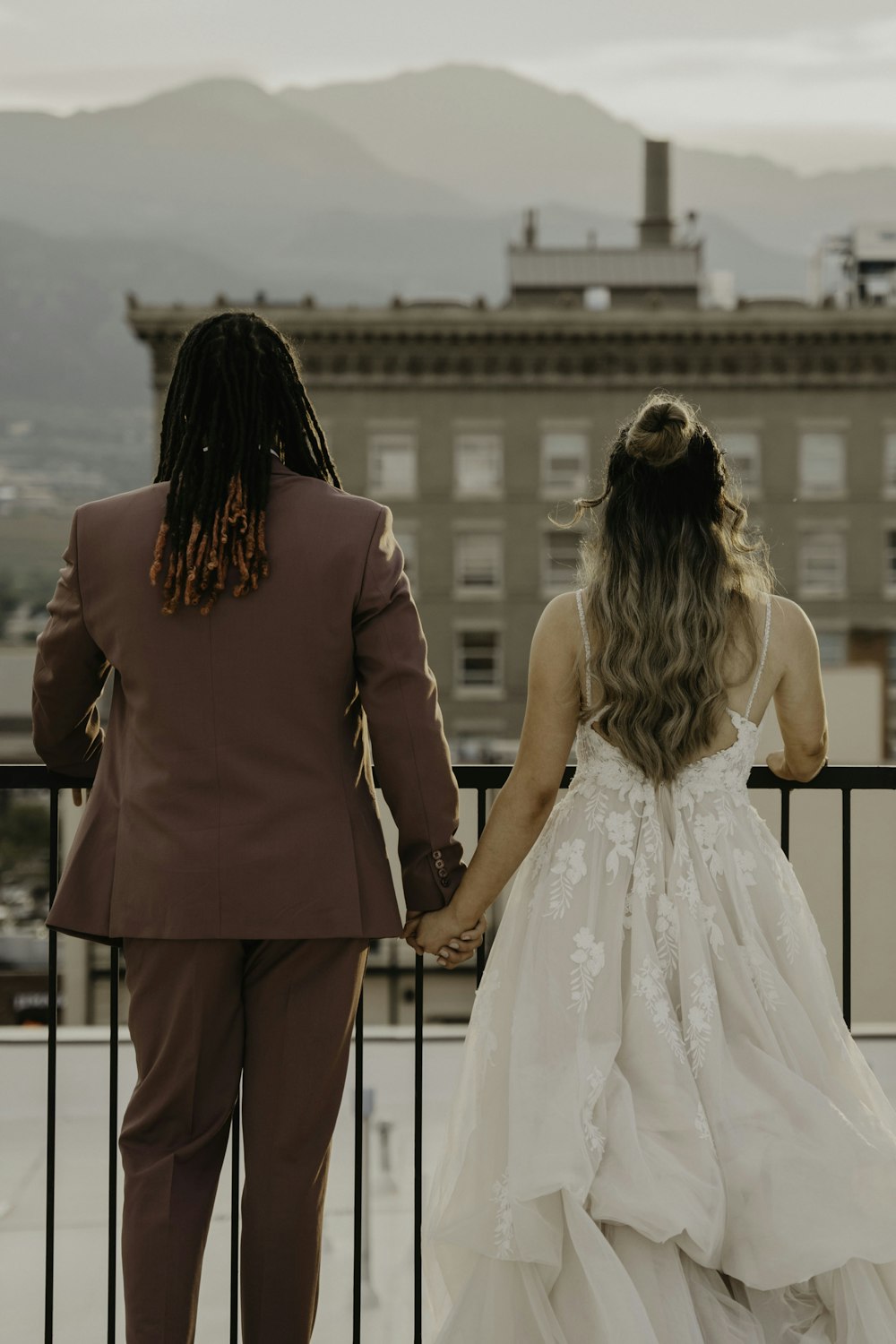 Una sposa e uno sposo si tengono per mano mentre si trovano su un balcone