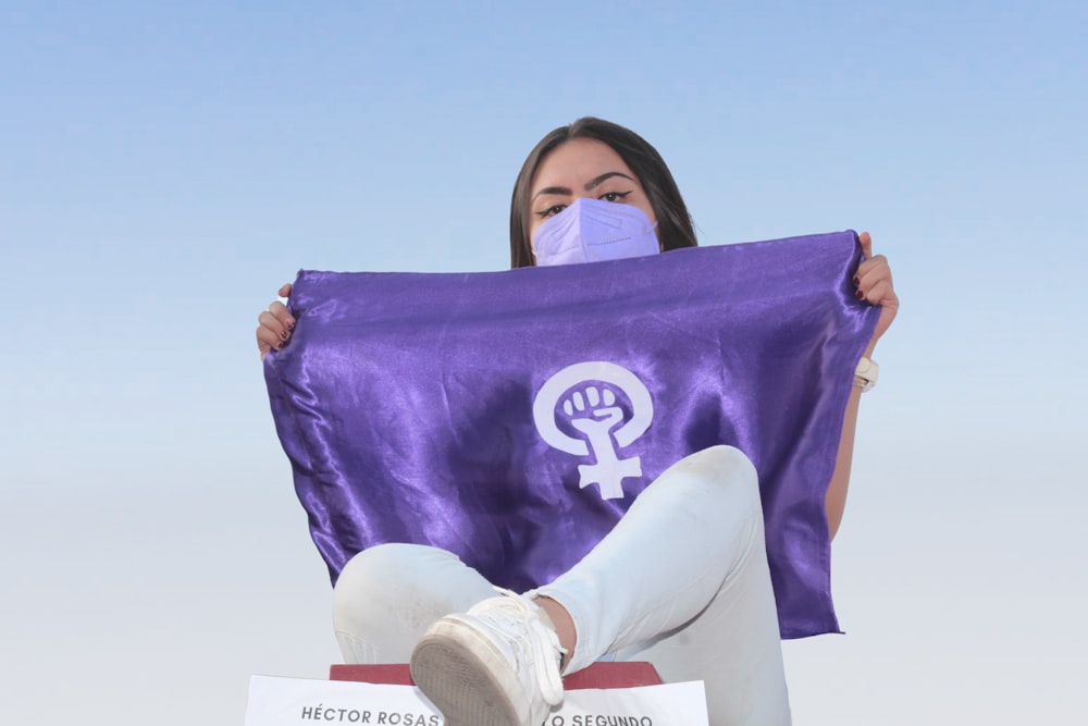 a woman sitting on a bench holding a purple flag