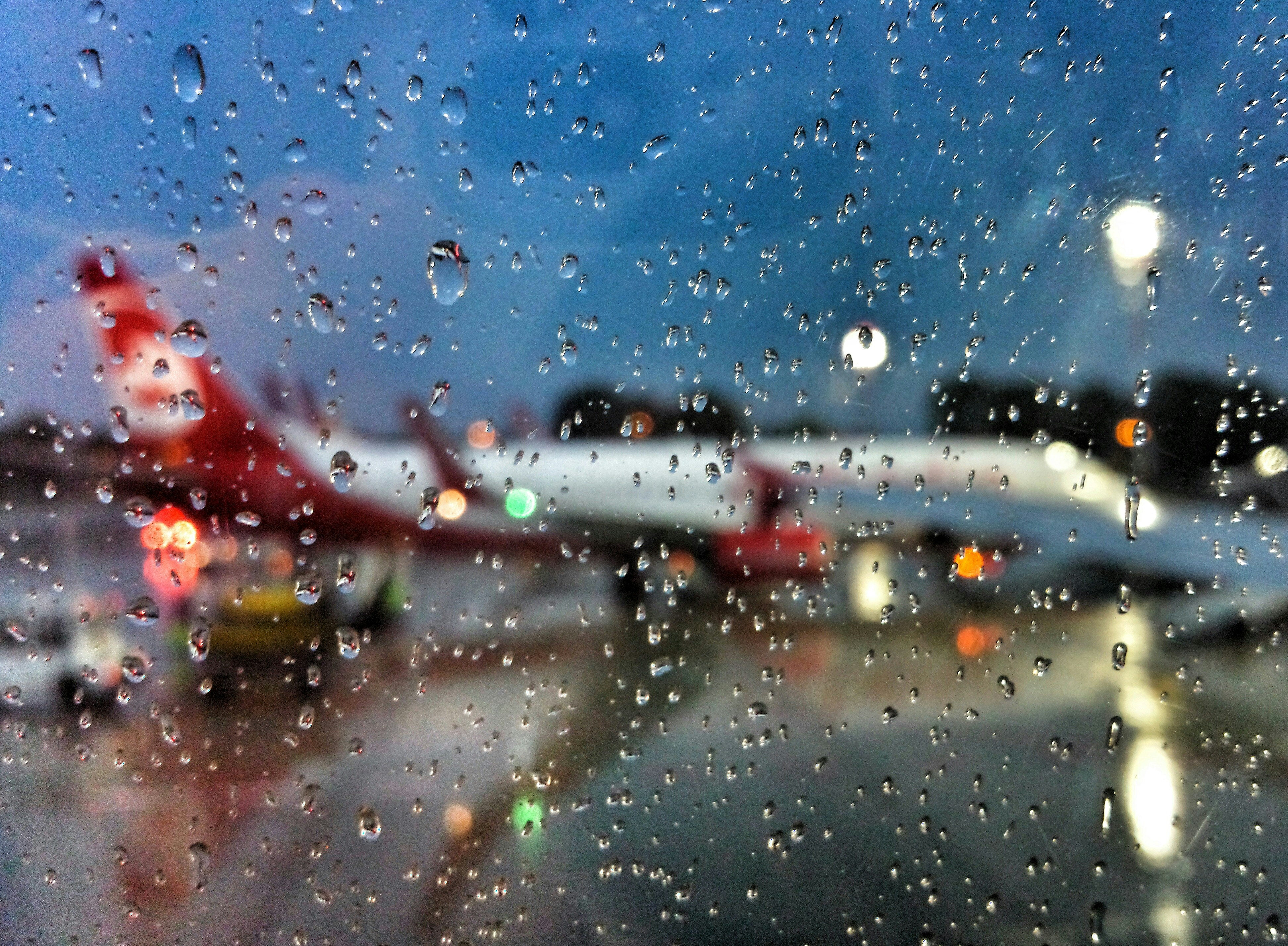 a view of an airport through a rain covered window, 