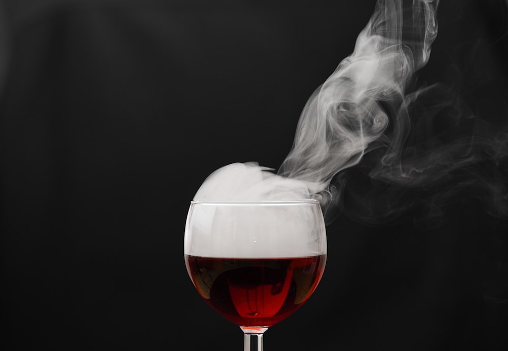 a glass of wine with smoke coming out of it