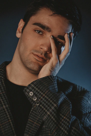 Portrait of James Stockborn-Hands with a contemplative expression against a shadowy background.