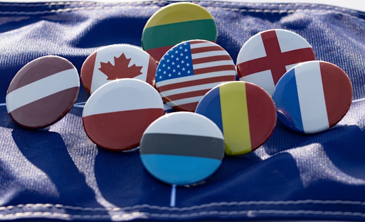 Flags of multiple study destinations displayed on colorful cards on a wooden table.