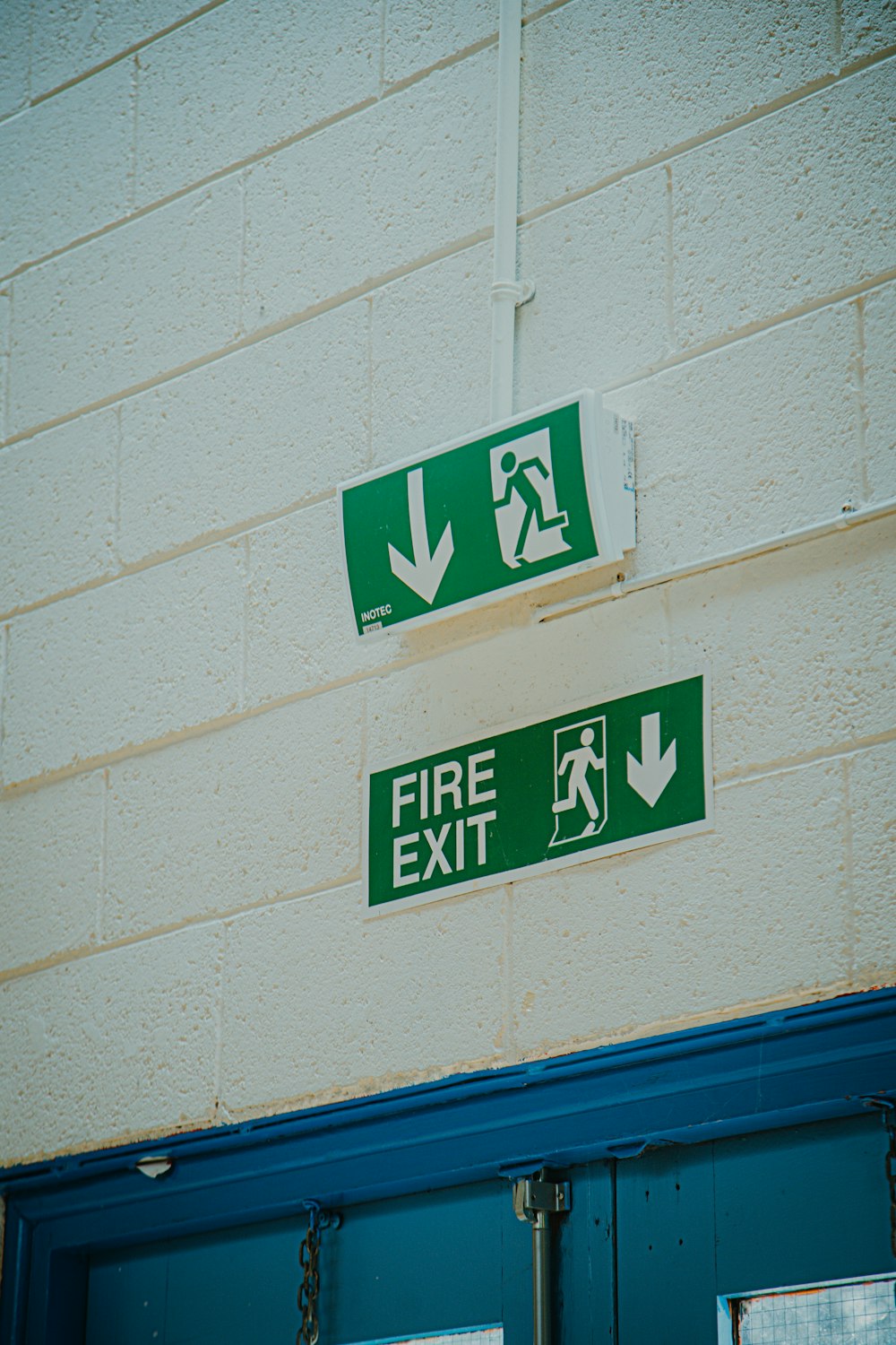 a green fire exit sign mounted to the side of a building