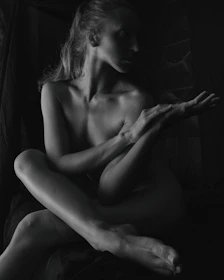 a naked woman sitting on top of a bed