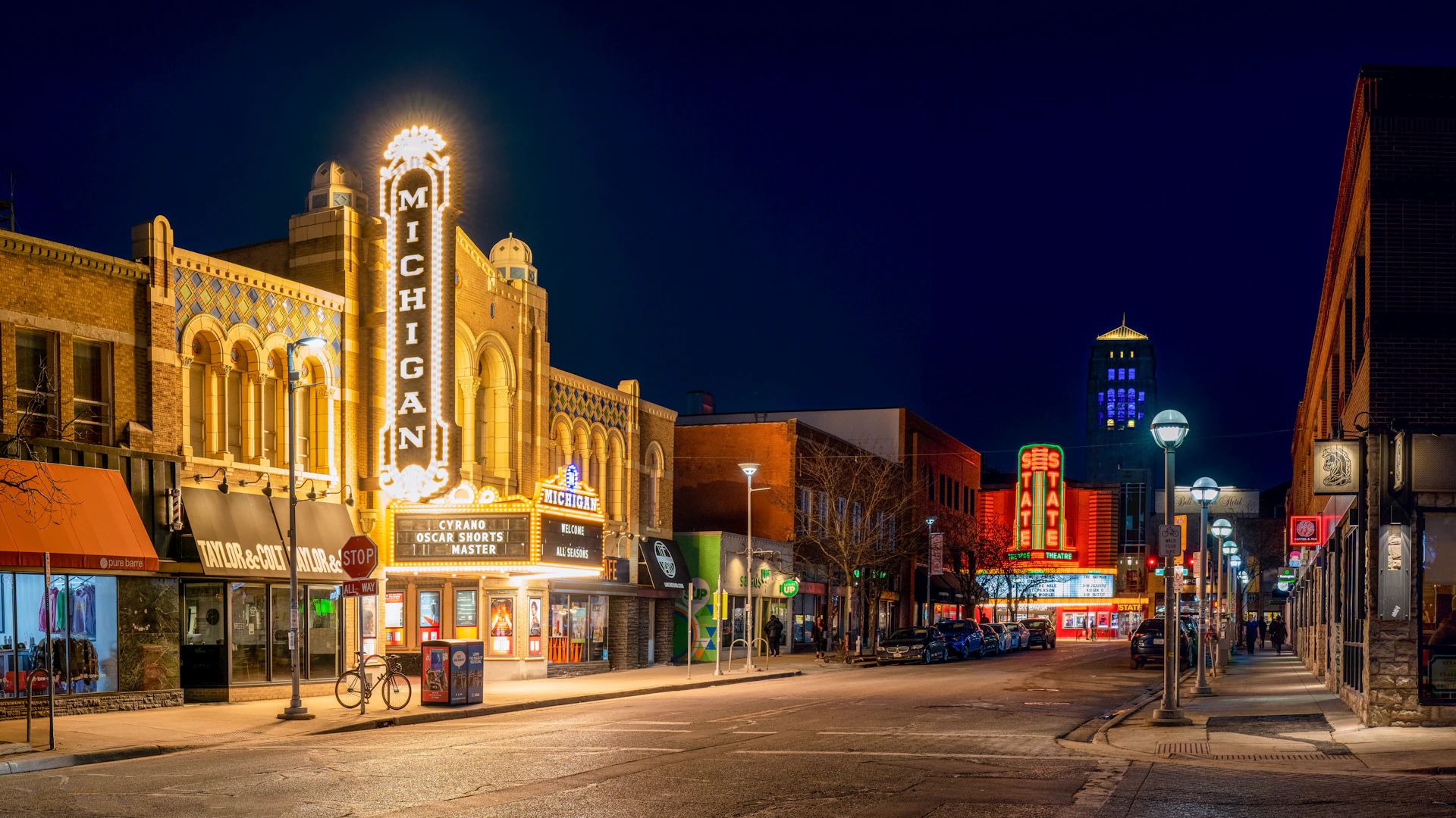 a city street at night with a theater sign lit up