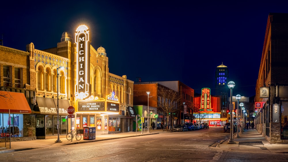 a city street at night with a theater sign lit up