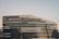 A modern architectural structure with a futuristic design, featuring sleek, curved lines and extensive glass panels. The building is identified as the Jockey Club Innovation Tower.