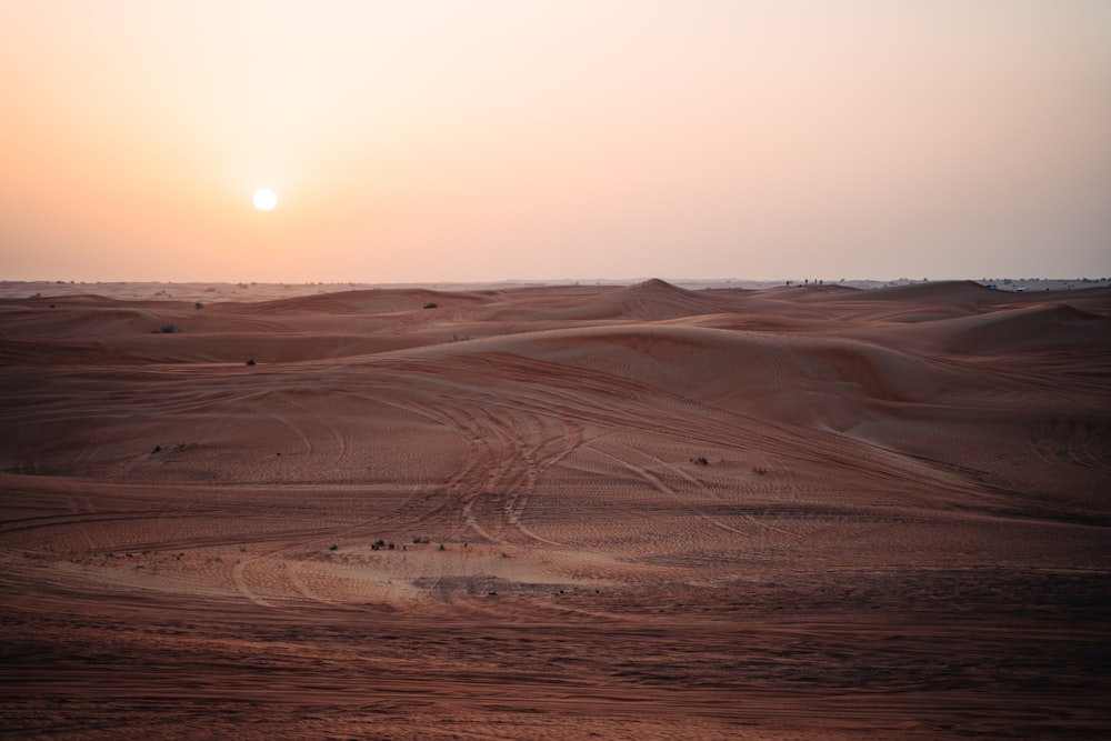 the sun is setting over the sand dunes