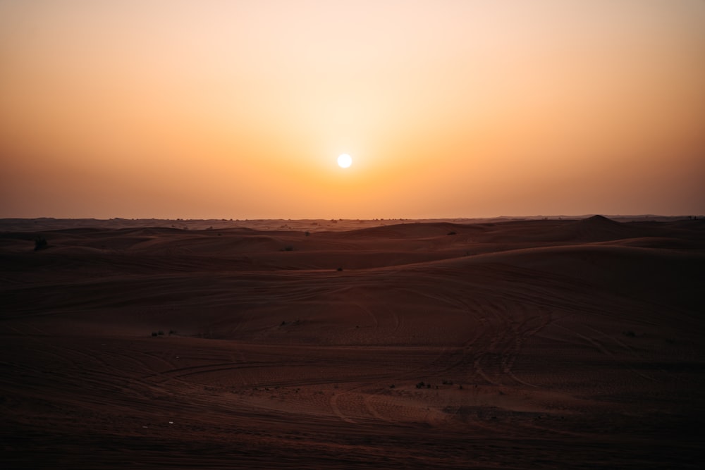 the sun is setting over a desert landscape