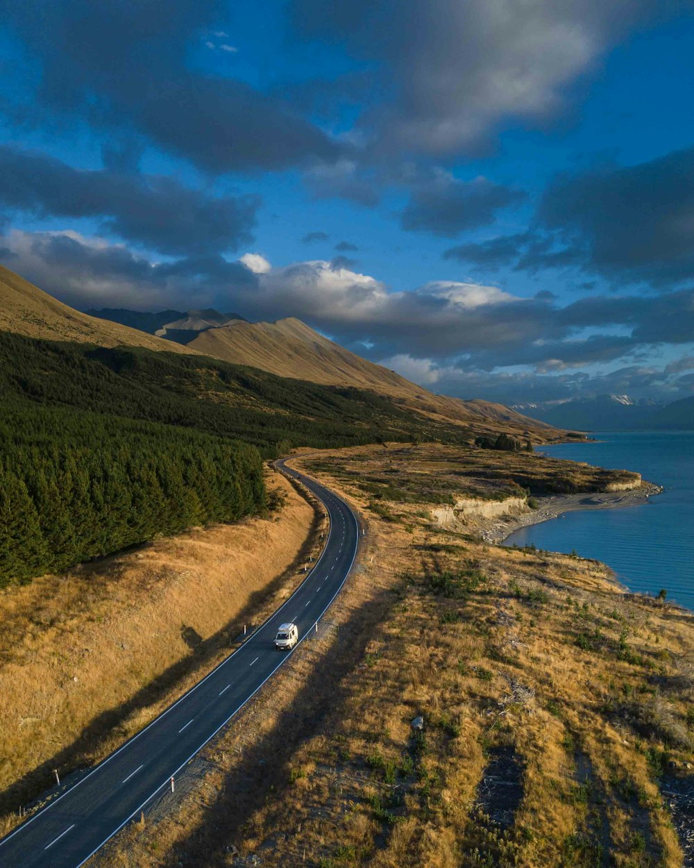 a car driving down a road next to a body of water