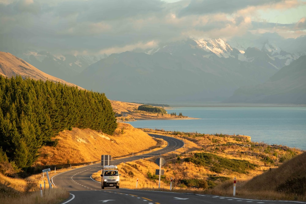 a truck driving down a road next to a lake