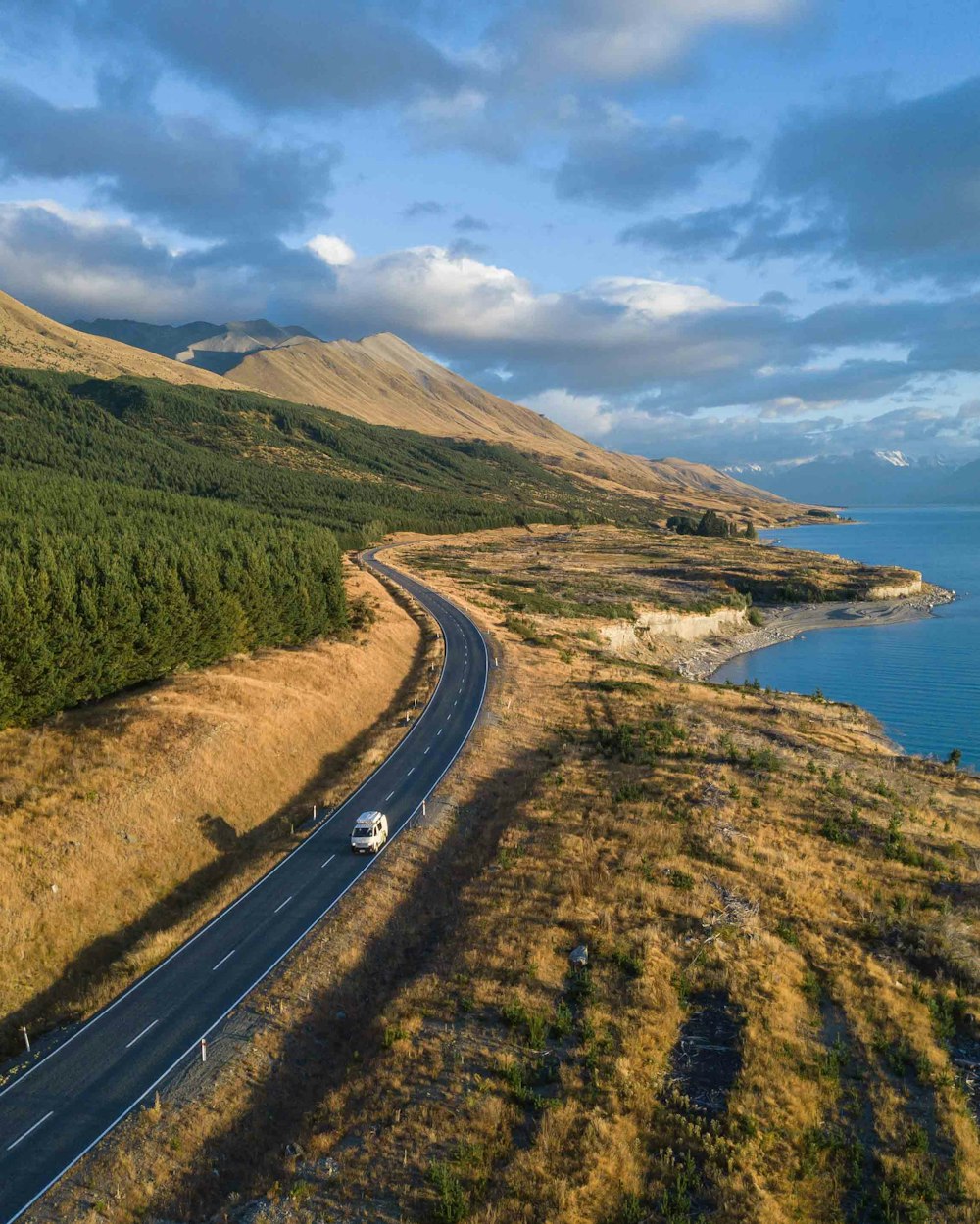 a car driving down a road next to a body of water