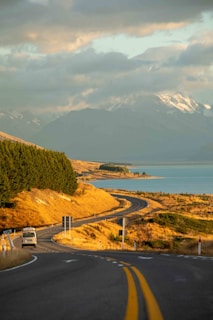 a truck driving down a road next to a lake