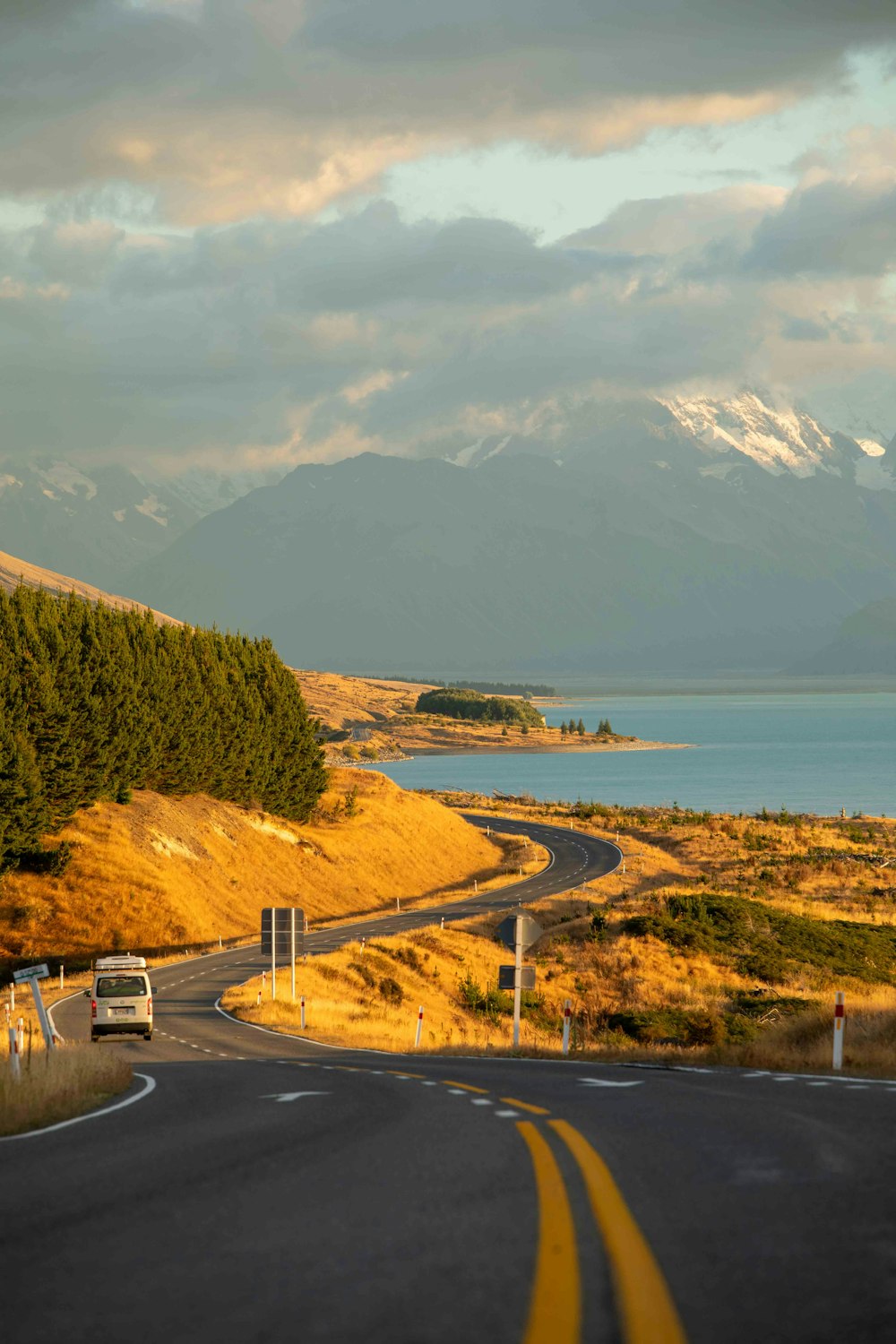 a truck driving down a road next to a lake