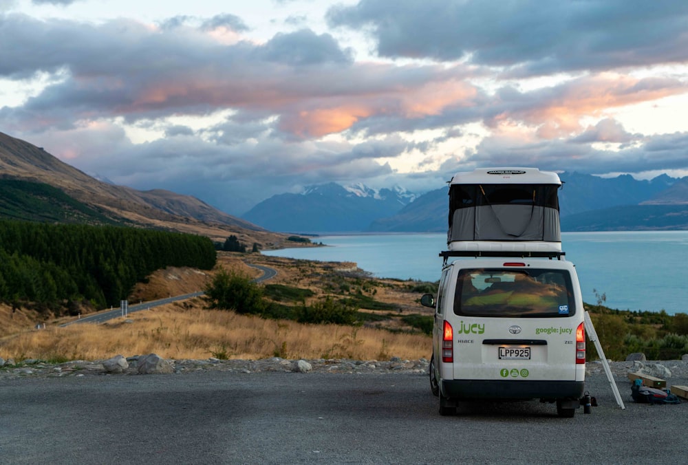 a van parked on the side of a road next to a body of water