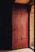 Rustic wooden door framed by a wrought iron archway in natural light.