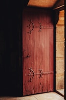 A rustic wooden door with iron hinges, set in a cozy cottage entrance.