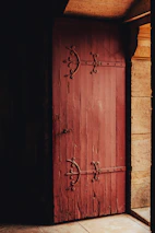 Close-up of a rustic wooden door with wrought iron details, hinting at the timeless charm within.