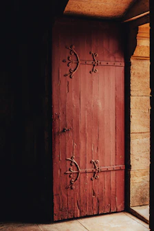 Close-up of a rustic wooden door with wrought iron details, hinting at the timeless charm within.