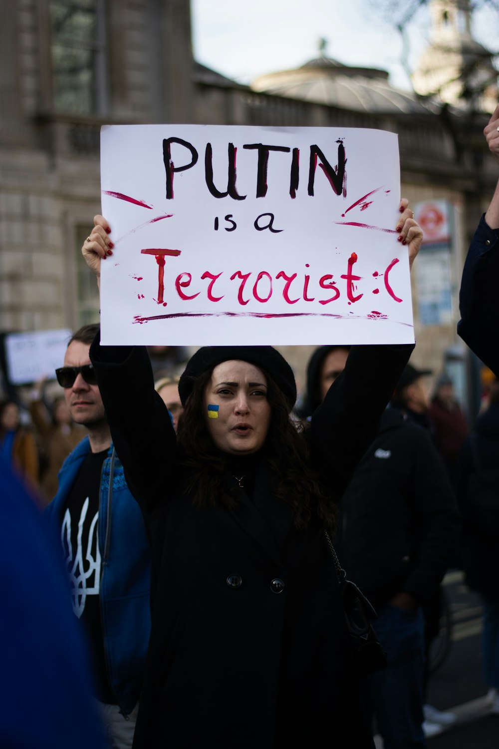 a woman holding a sign in the middle of a crowd